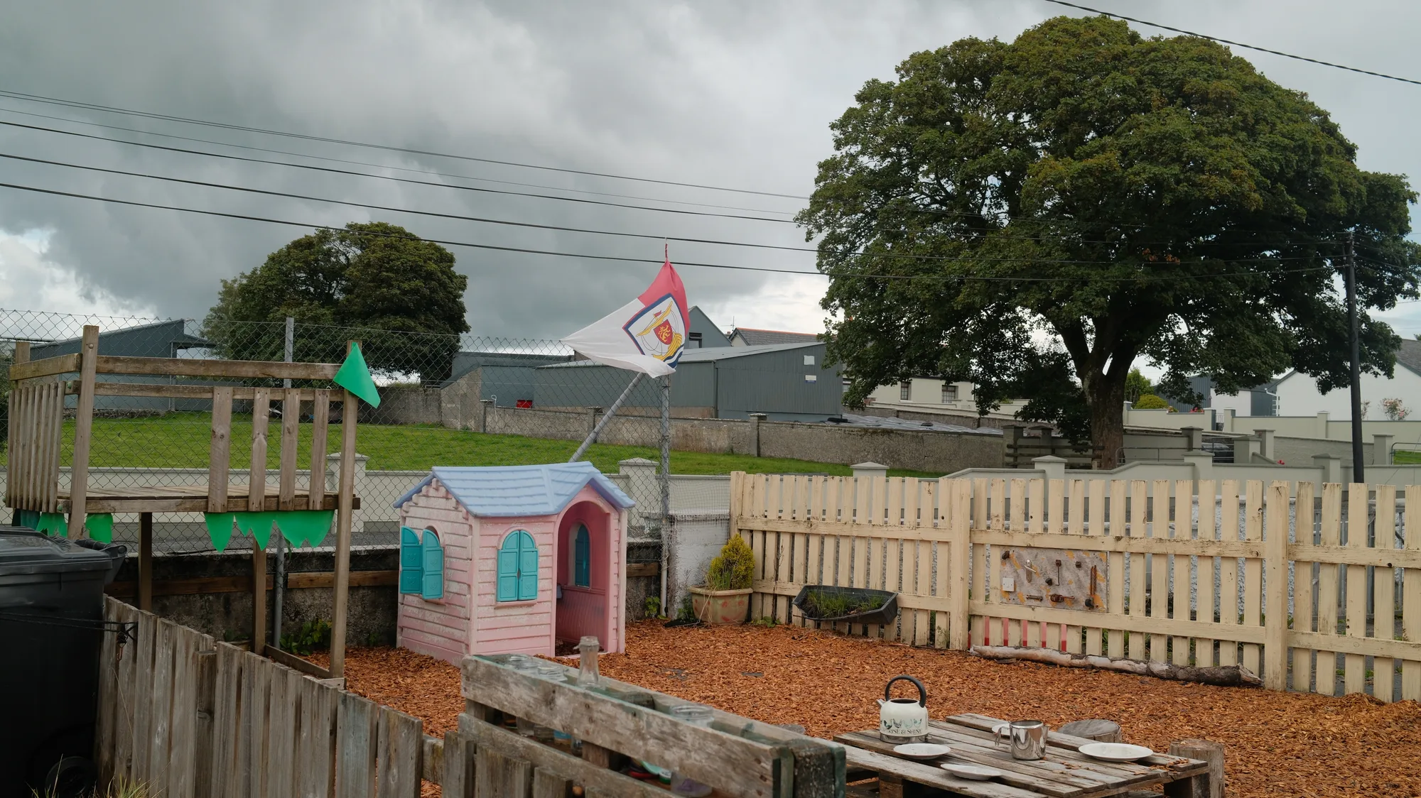 Small playhouses and outdoor work surfaces beside the fence