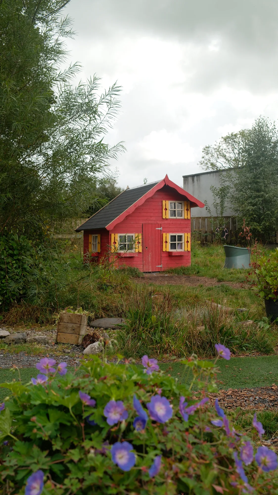 The red playhouse framed by flowers