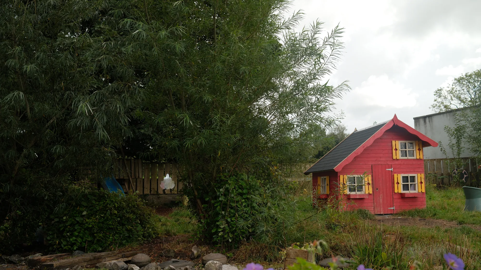 The red playhouse beneath the large tree