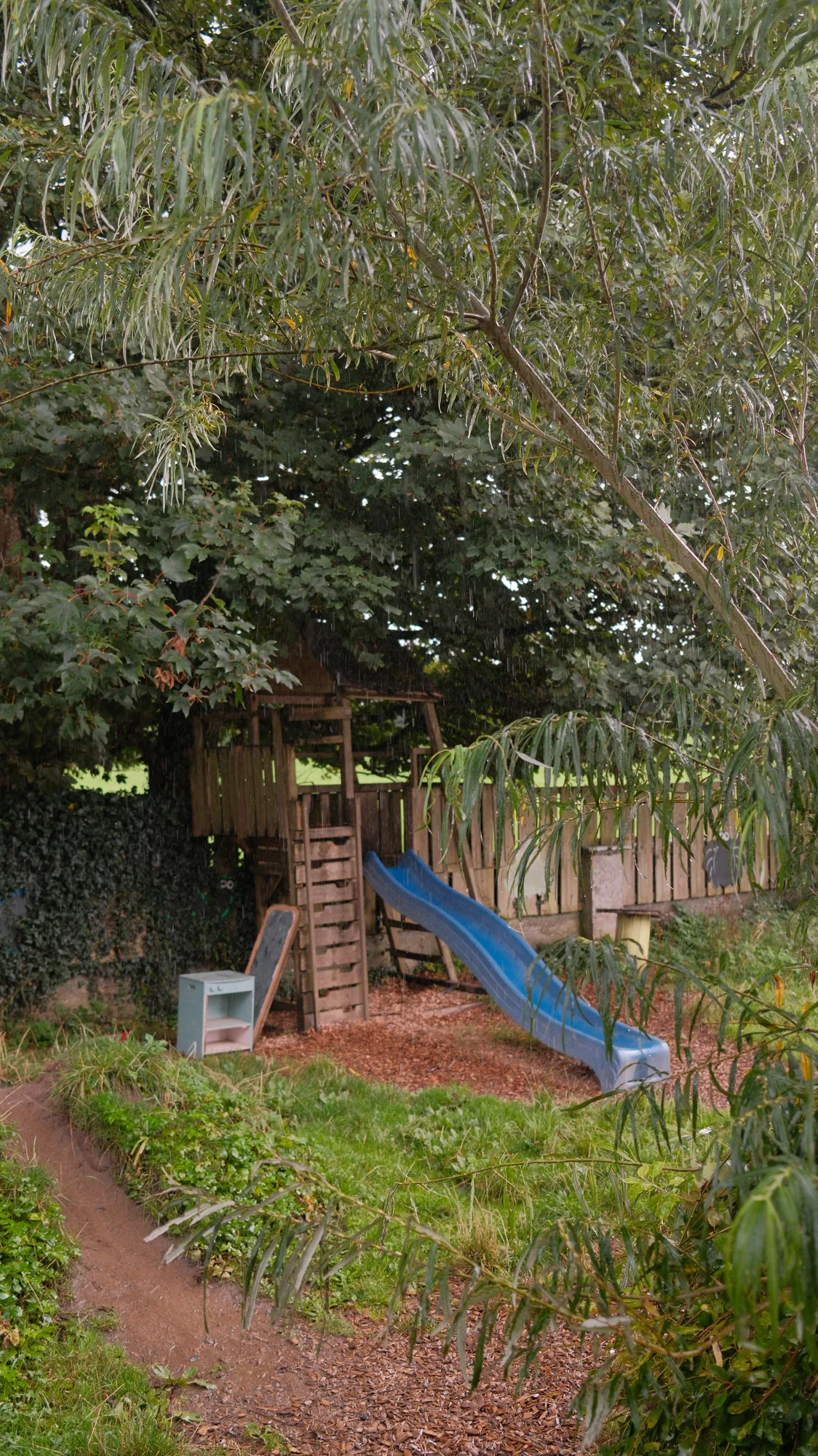 The slide beneath the trees at the garden edge
